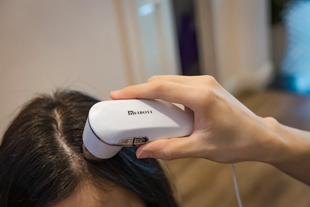 Close-up of a handheld device being used on the scalp