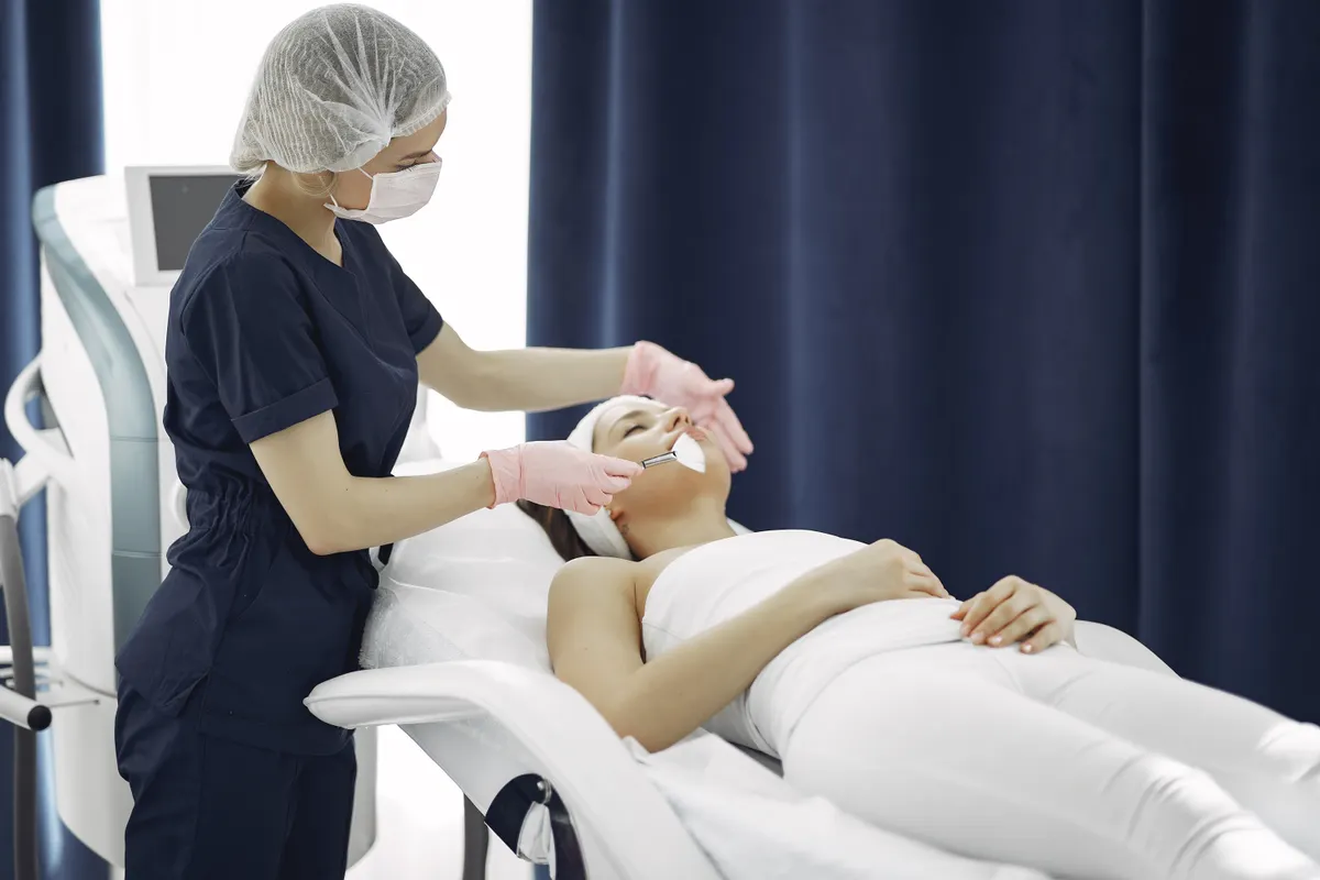 A professional providing a facial treatment in a clinical setting